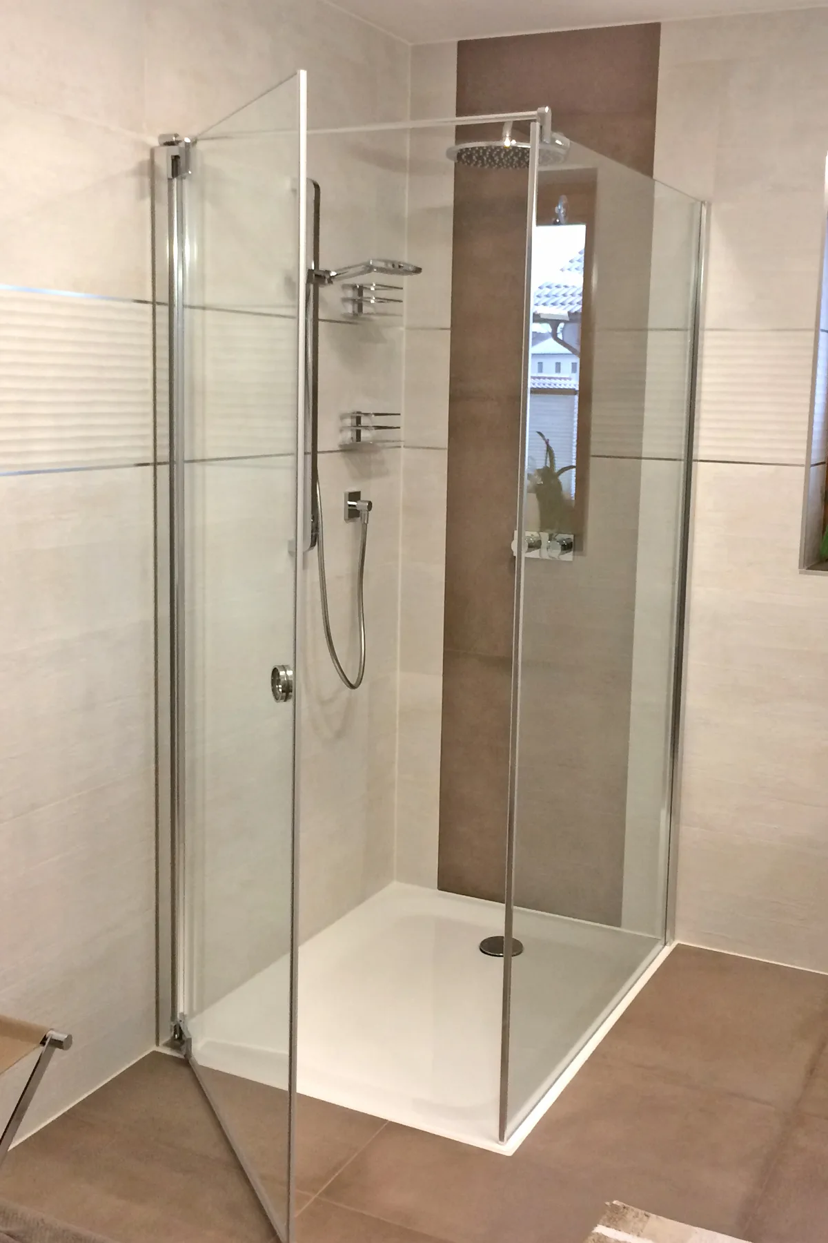 Eckdusche aus Glas mit Regenbrause und Handbrause, helle Fliesen mit dunklem Streifen