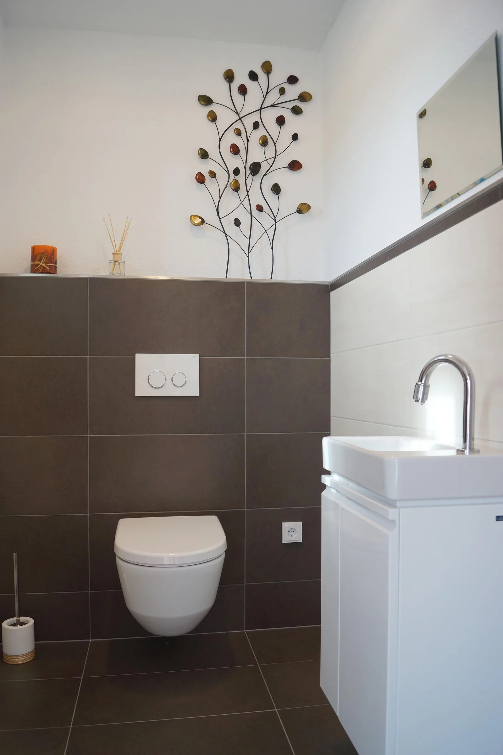 Gäste-WC mit dunkelbraunen Wandfliesen, Hänge-WC und kleinem weißem Waschtisch